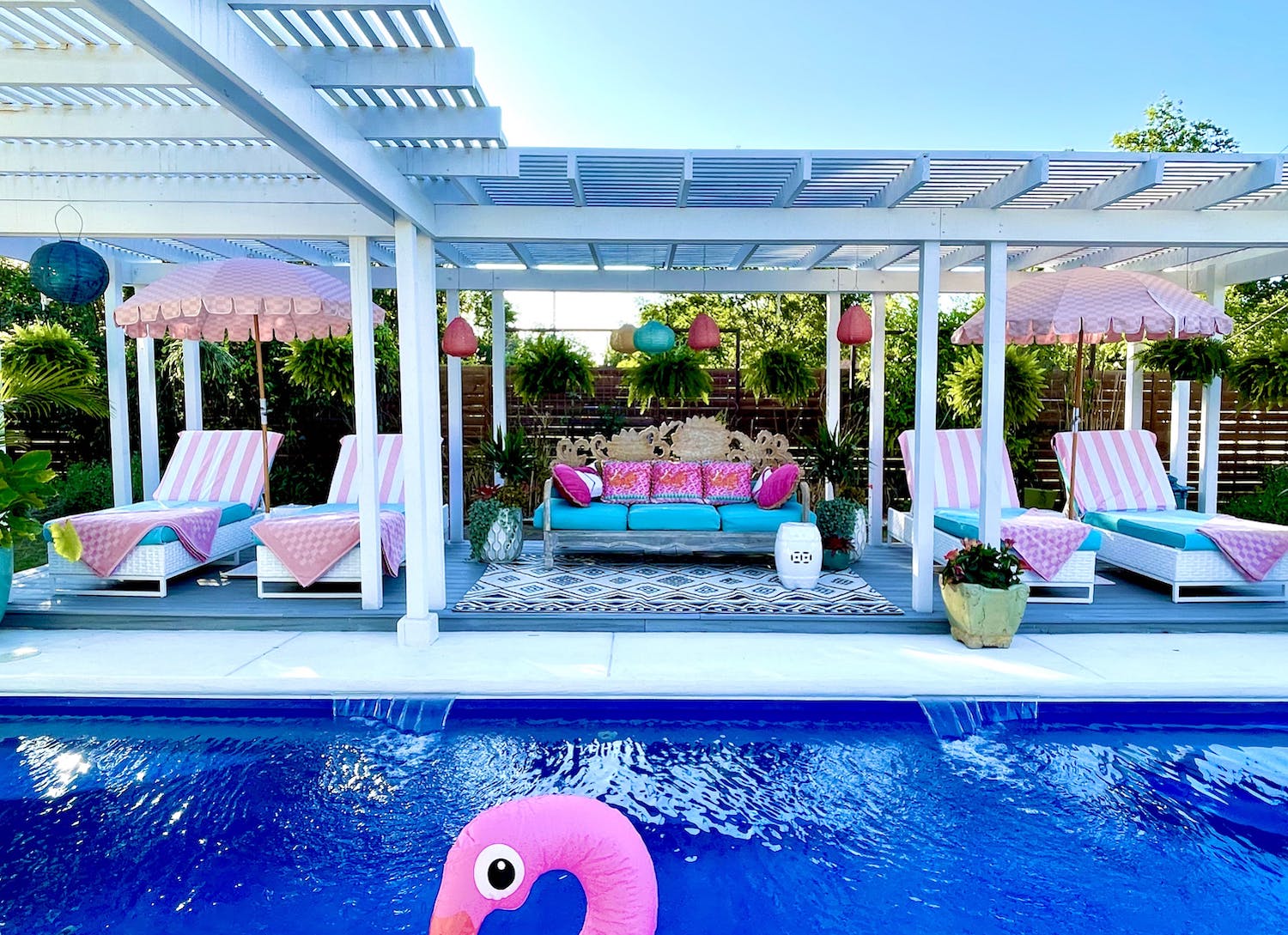 Pool with pink furniture and flamingo float under a cabana. 