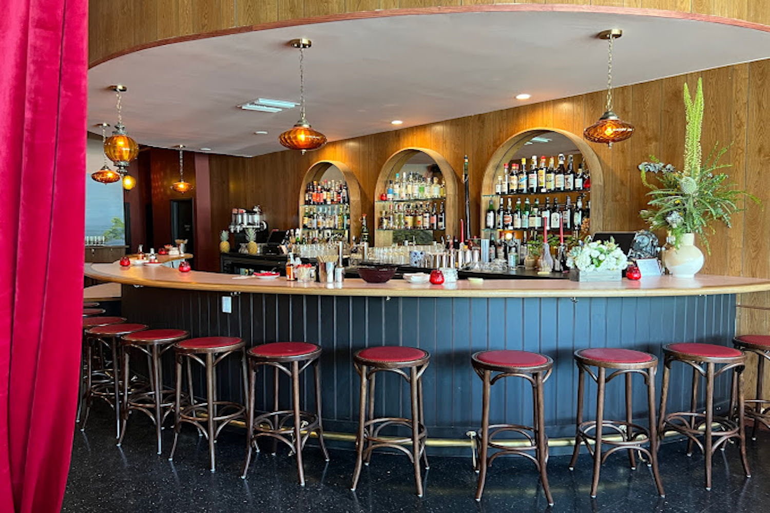 Bar area with arches in walls for bottles and red bar stools.