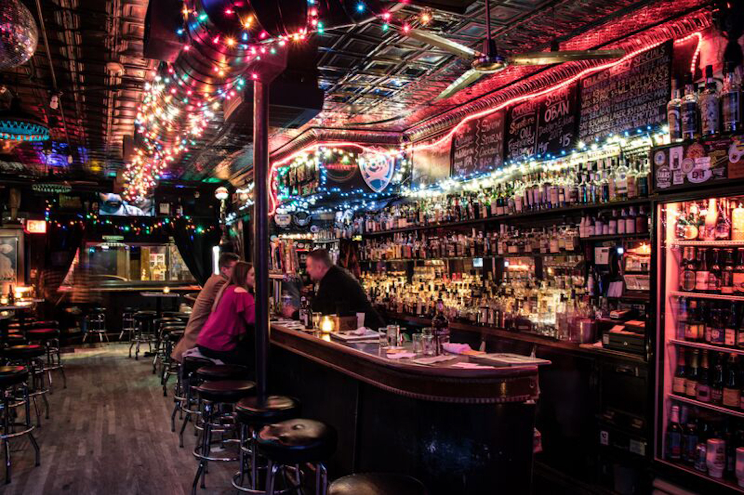 Dimly lit bar area surrounded by bright and colorful string lights.