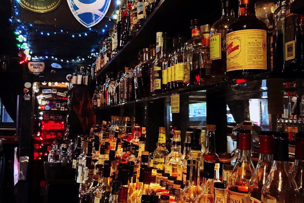 Rows of whiskey on a shelf behind a bar