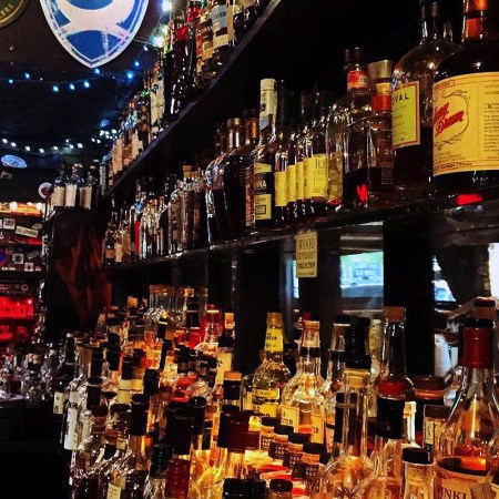 Rows of whiskey on a shelf behind a bar