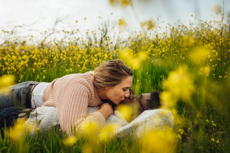 Loving couple kissing on flowering meadow outdoors
