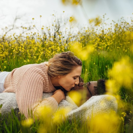 Loving couple kissing on flowering meadow outdoors