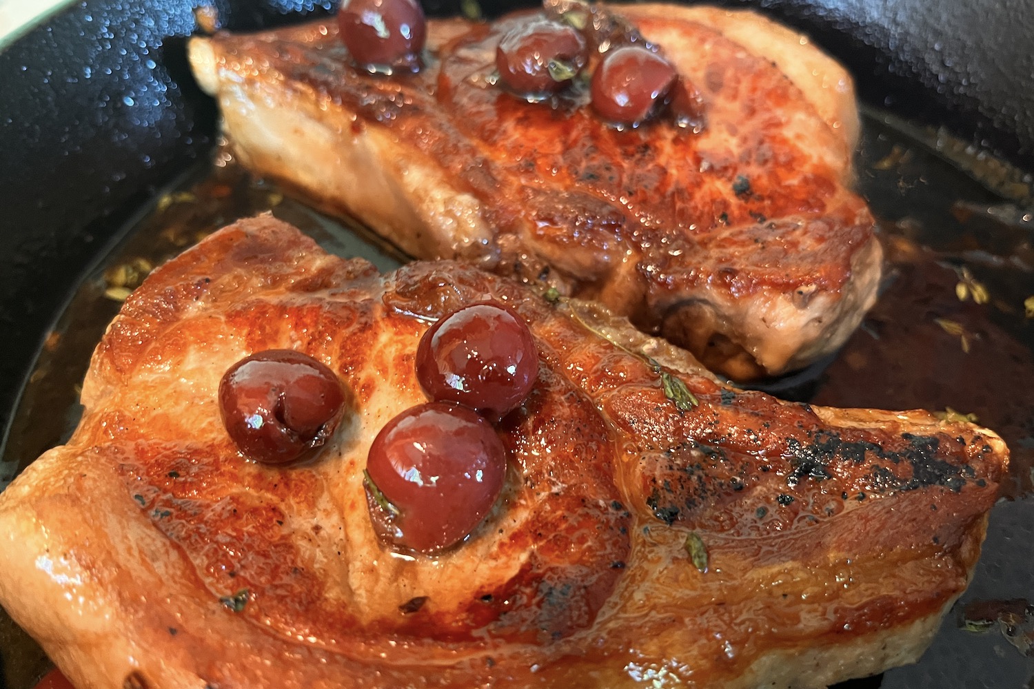 pork chops in a cast iron pan with cherry sauce
