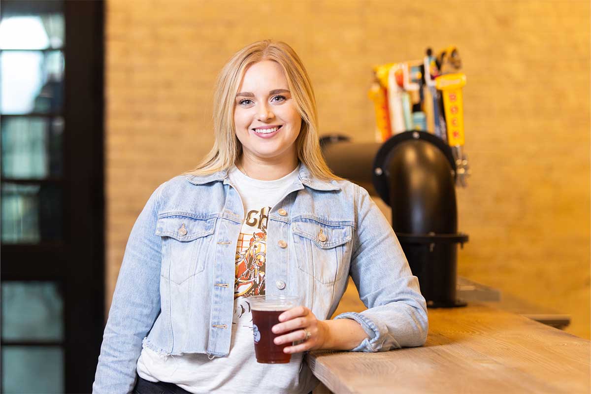 Jessica Michalec, the Head of Distilling Operations at Shiner, holding a beer inside the brewery