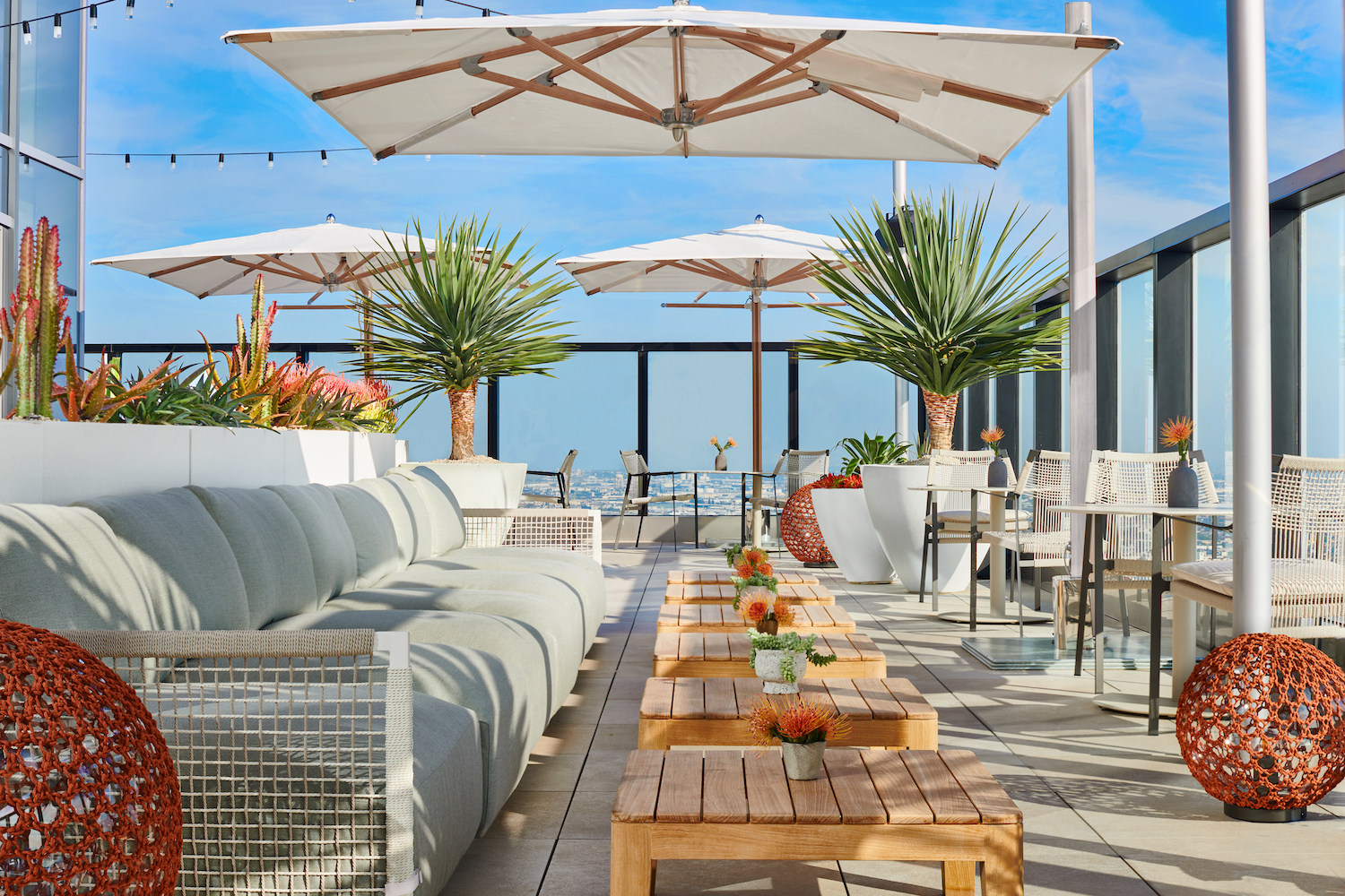 Rooftop bar area with big couches and umbrellas.