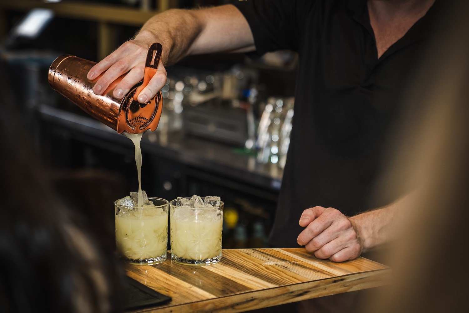 a bartender pouring two tequila drinks