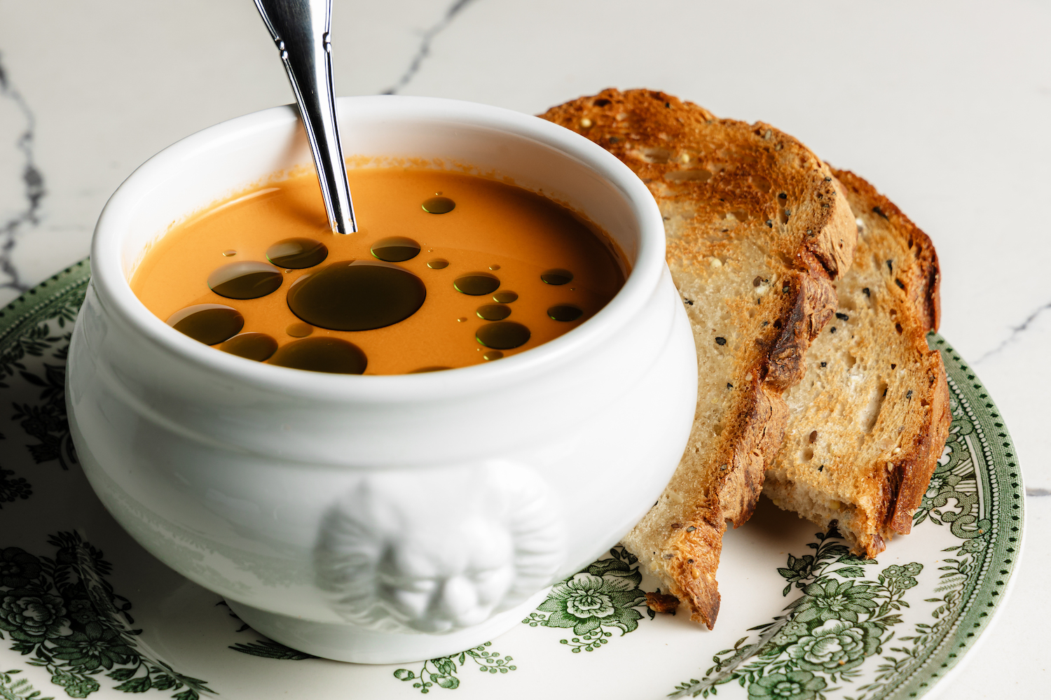 soup in a bowl with bread on the side.