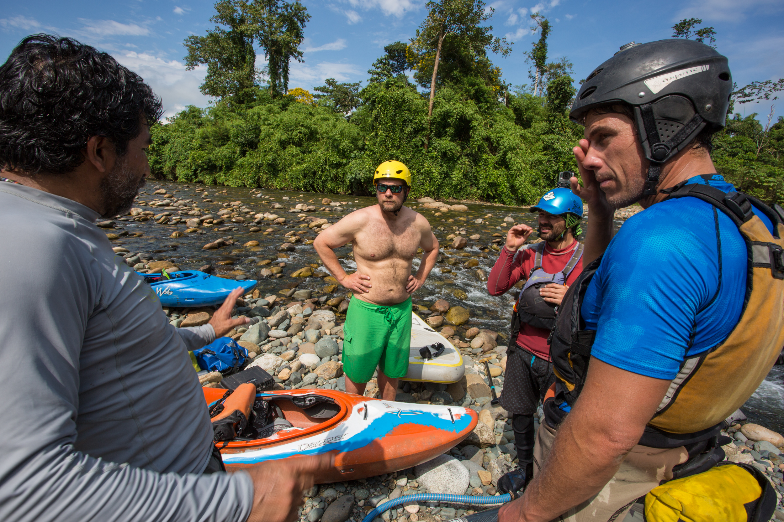 A group of SUP paddleboarders on the bank of the Madre de Dios River in Peru discuss a course