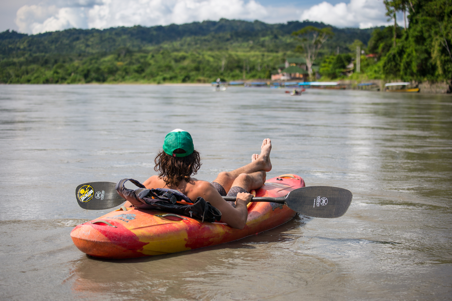 A paddleboarder looks down the Madre de Dios river in Peru at a group of others in the distance