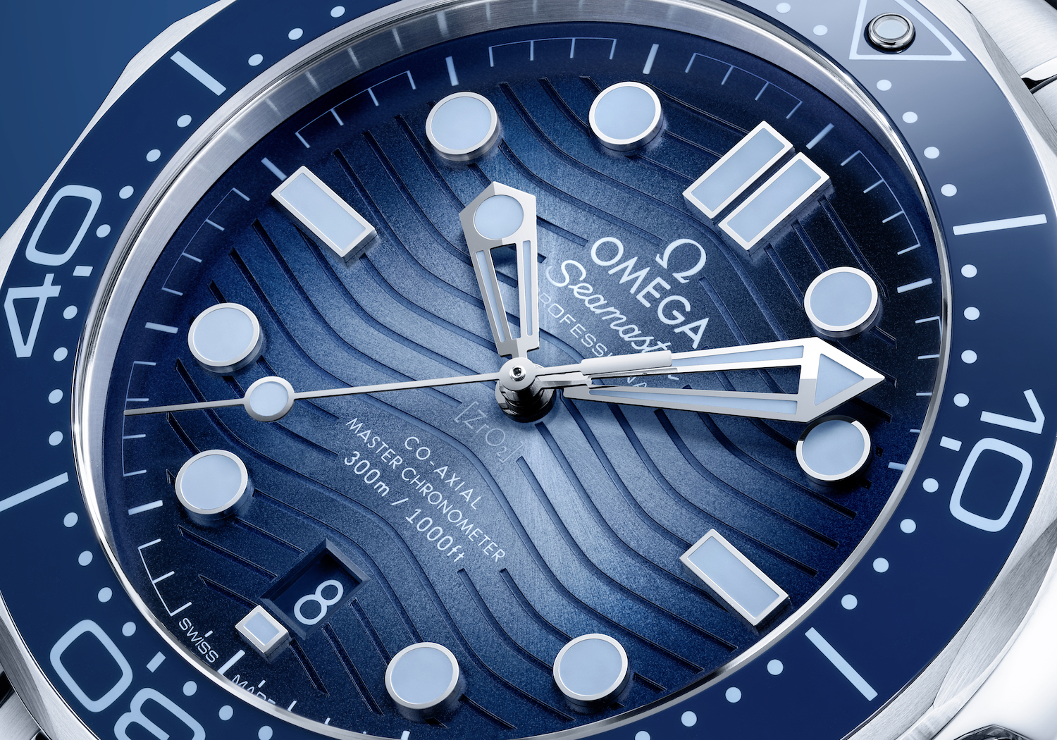 Up-close shot of watch face with multiple shades of blue and design features resembling ocean waves.