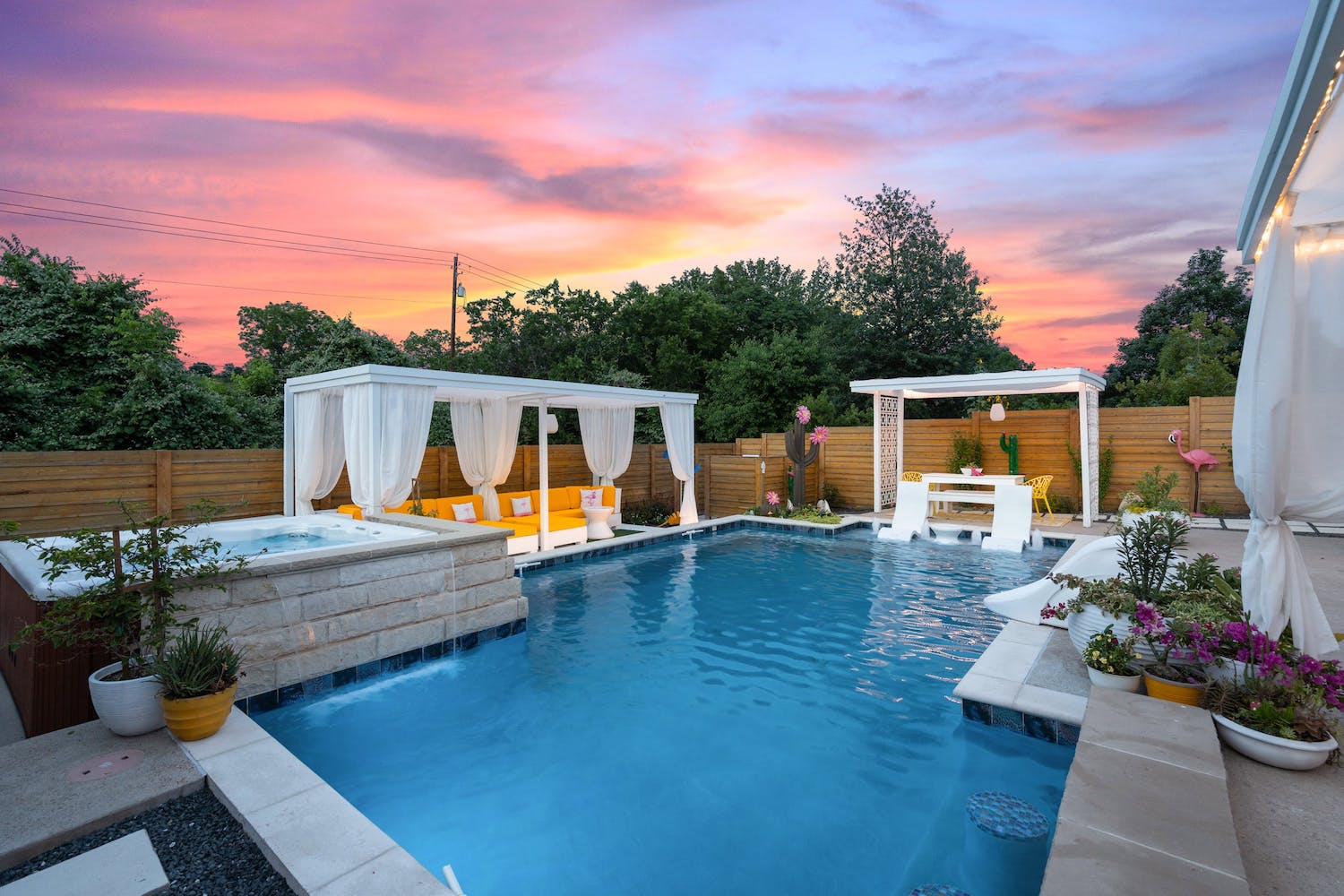 Pool at sunset with cabanas, couches, a hot tub and chairs