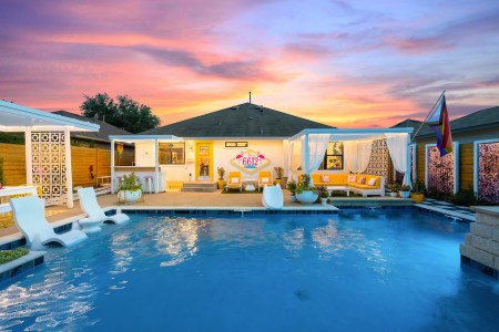 pool underneath a sunset with chairs and a cabana