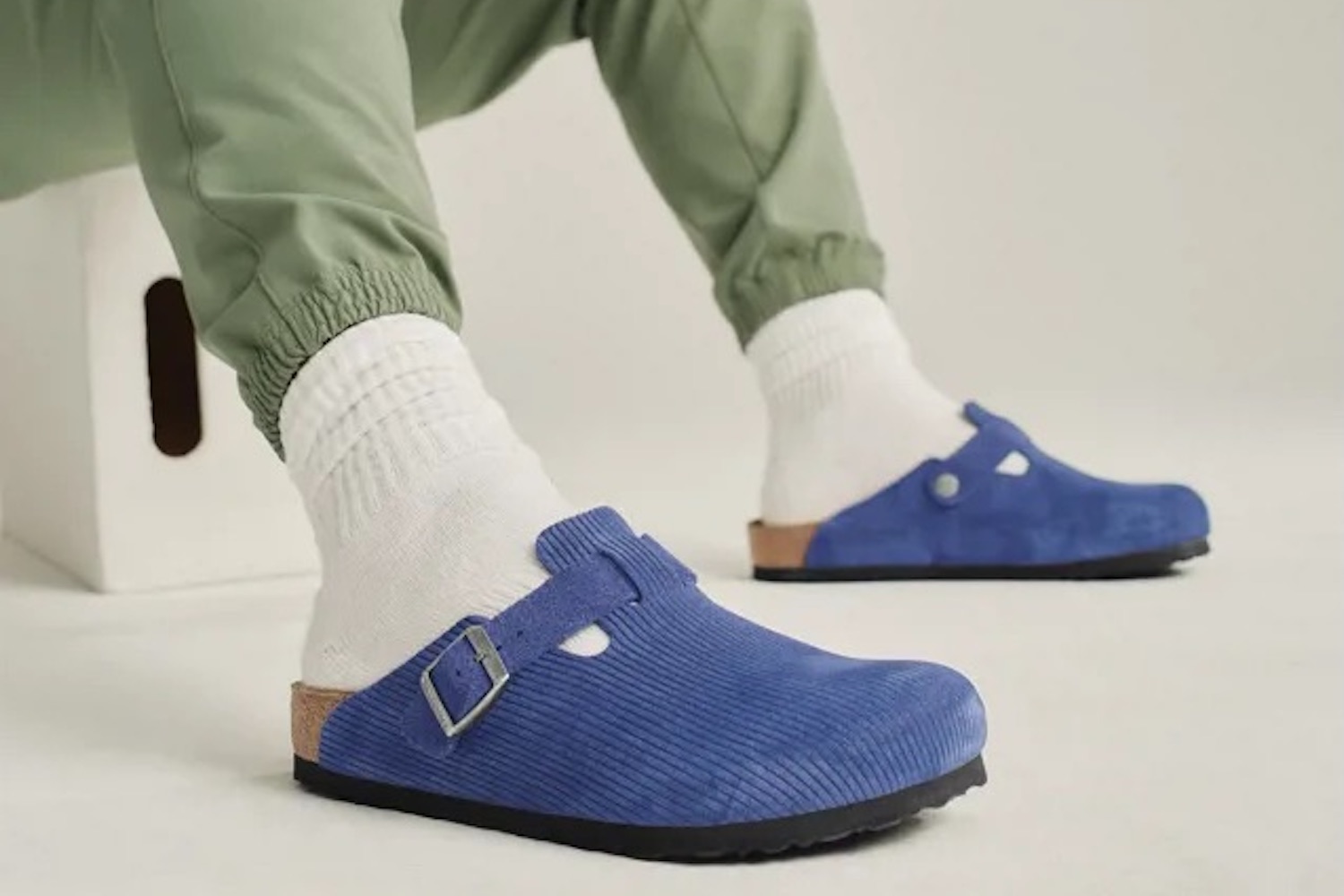 a model in a pair of Birkenstock Boston Corduroy slides on a grey background