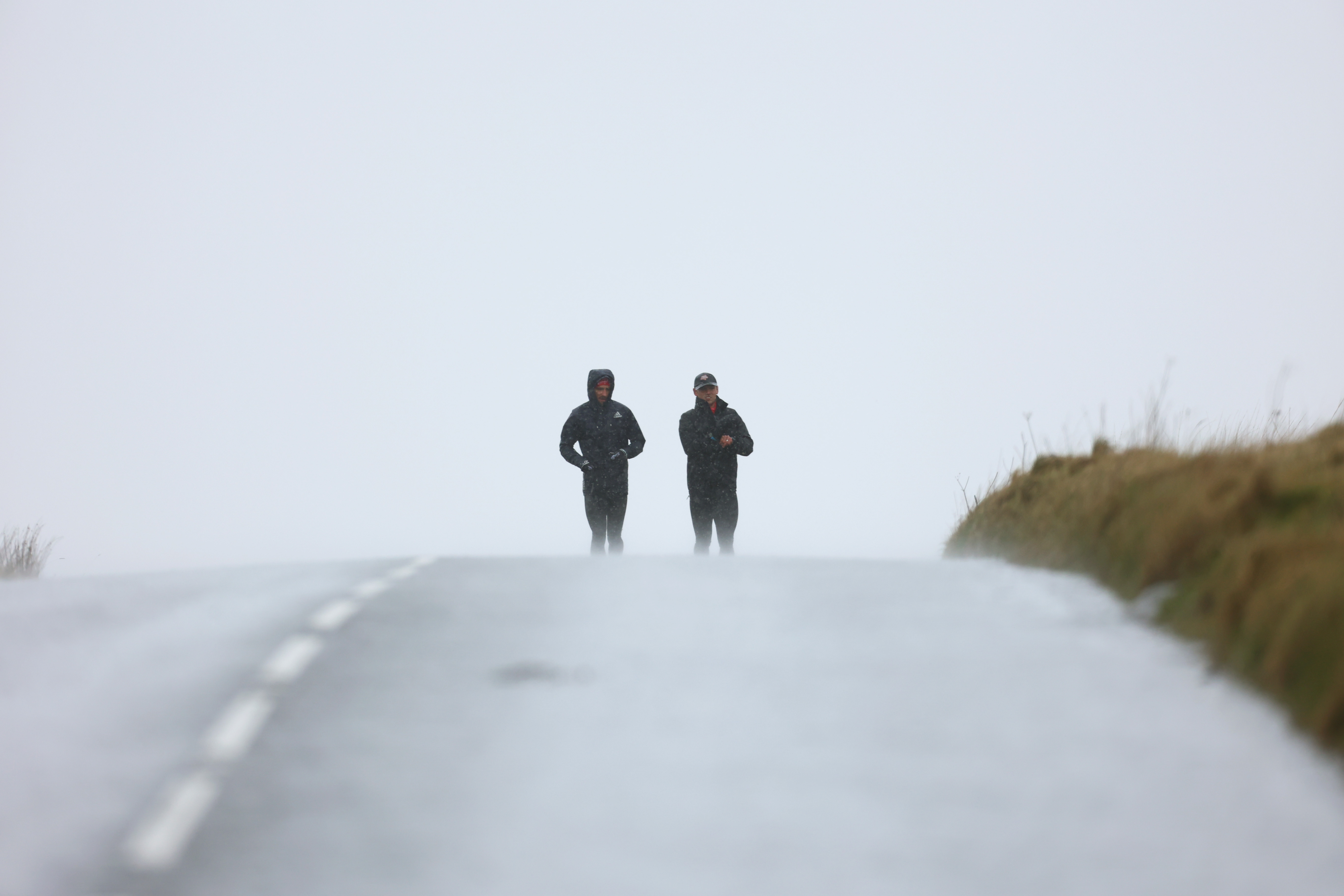 A pair of runners climbing a hill in the fog.