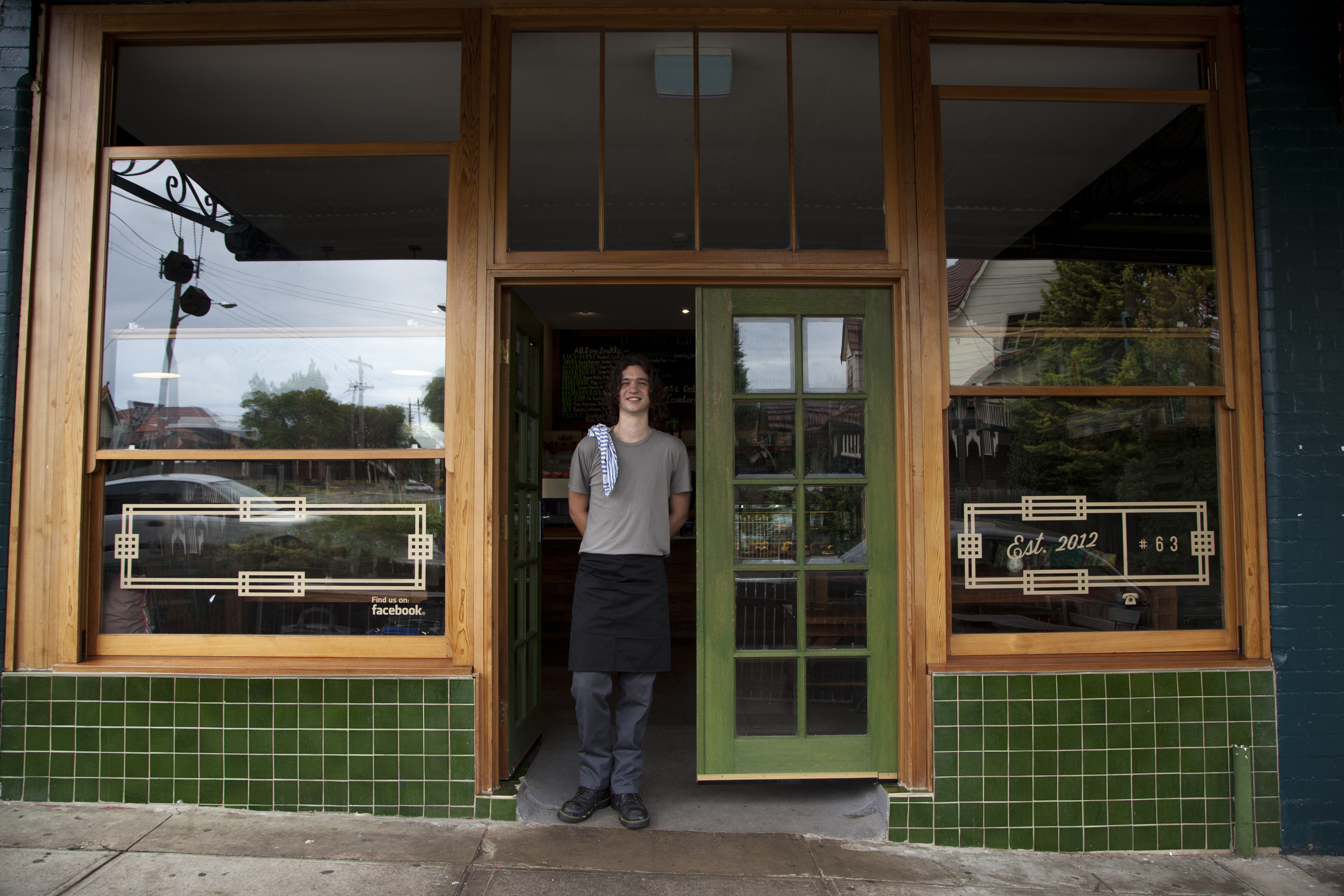 A man standing in the threshold of a restaurant.