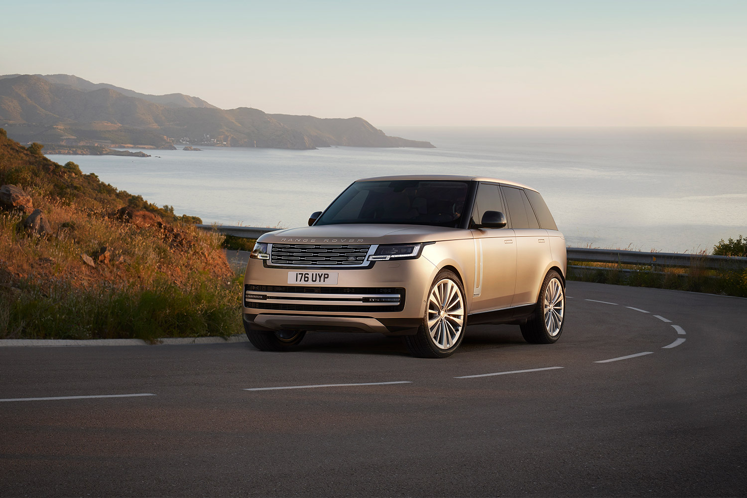 The 2023 Land Rover Range Rover SUV driving up a road next to the ocean