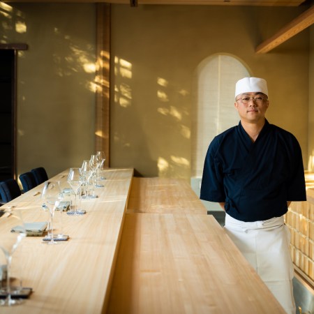 Chef Shingo Akikuni standing next to bar in the restaurant