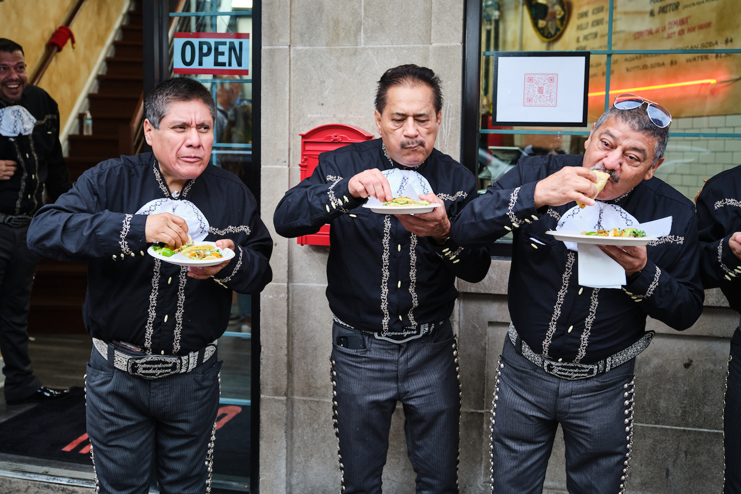Group of men eating a tacos outside