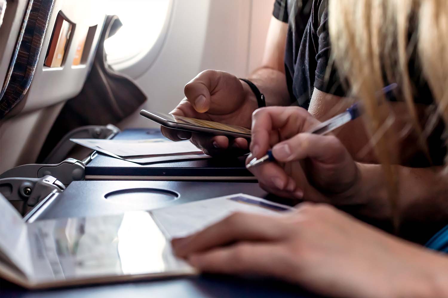 Airplane passengers filling out immigration and customs forms on the plane