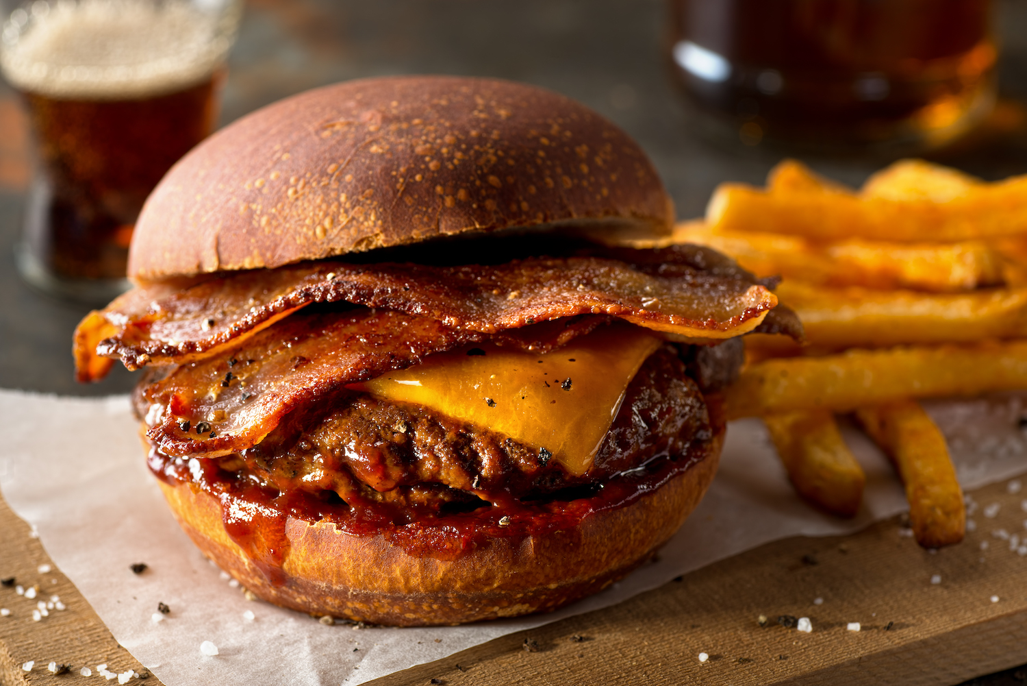 Bacon cheeseburger with cherry barbecue sauce and fries in the background 