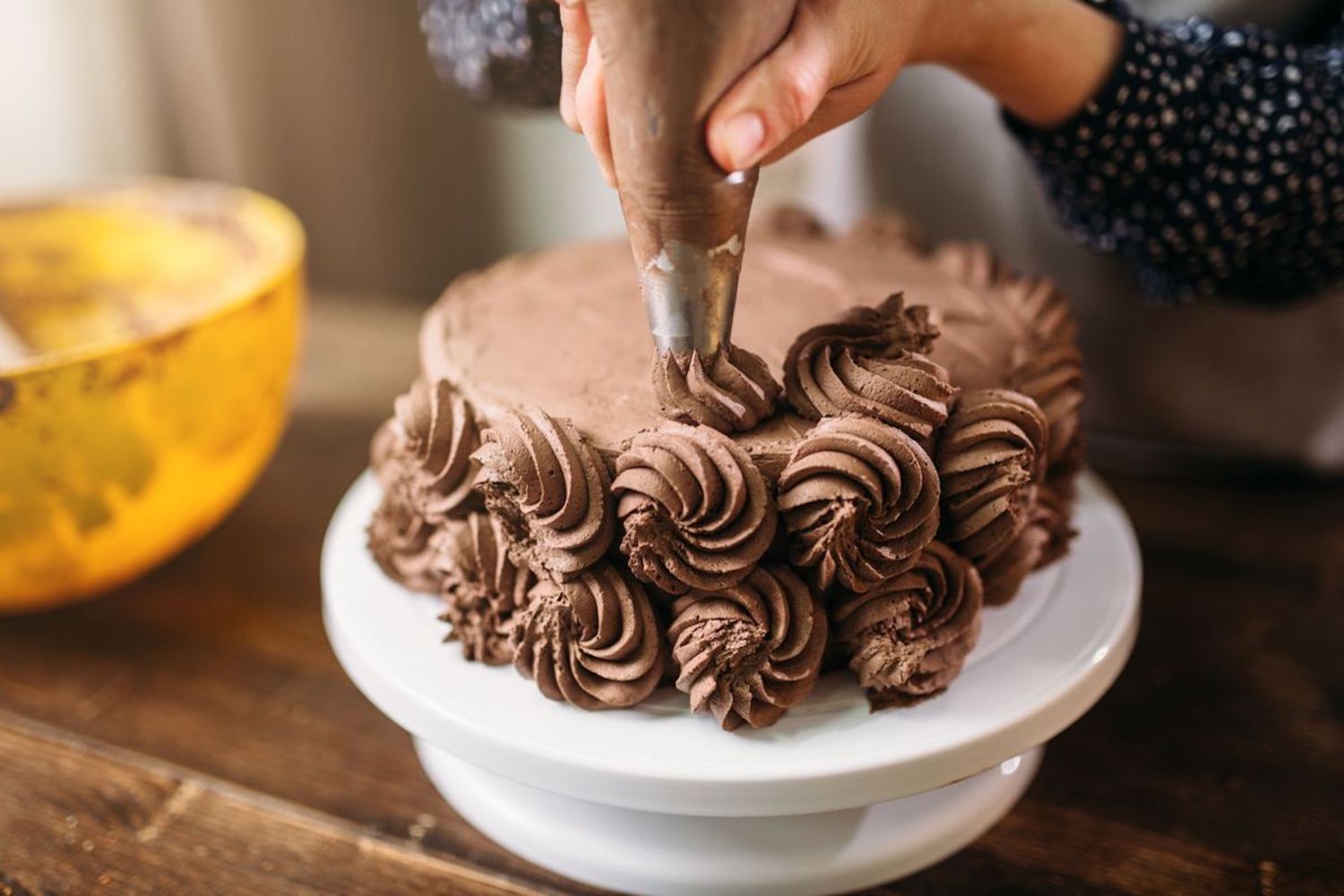 a hand decorating a chocolate cake