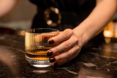 A woman holding a glass of whisky. A new survey of people in the whisky industry suggests that sexism is rampant and a woman's knowledge about whisky is often questioned.