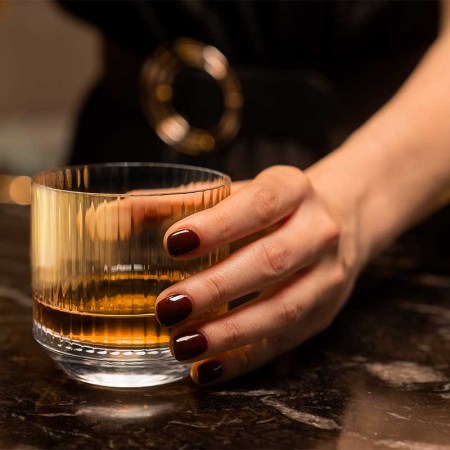 A woman holding a glass of whisky. A new survey of people in the whisky industry suggests that sexism is rampant and a woman's knowledge about whisky is often questioned.