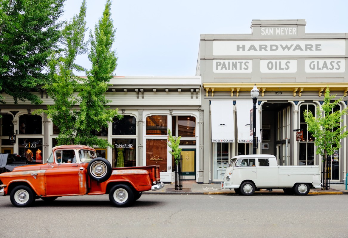Exterior of row of shops on a street with old cars.