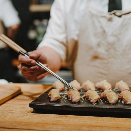 Sushi on a board being arranged with chopsticks by a chef with Sushi by Scratch