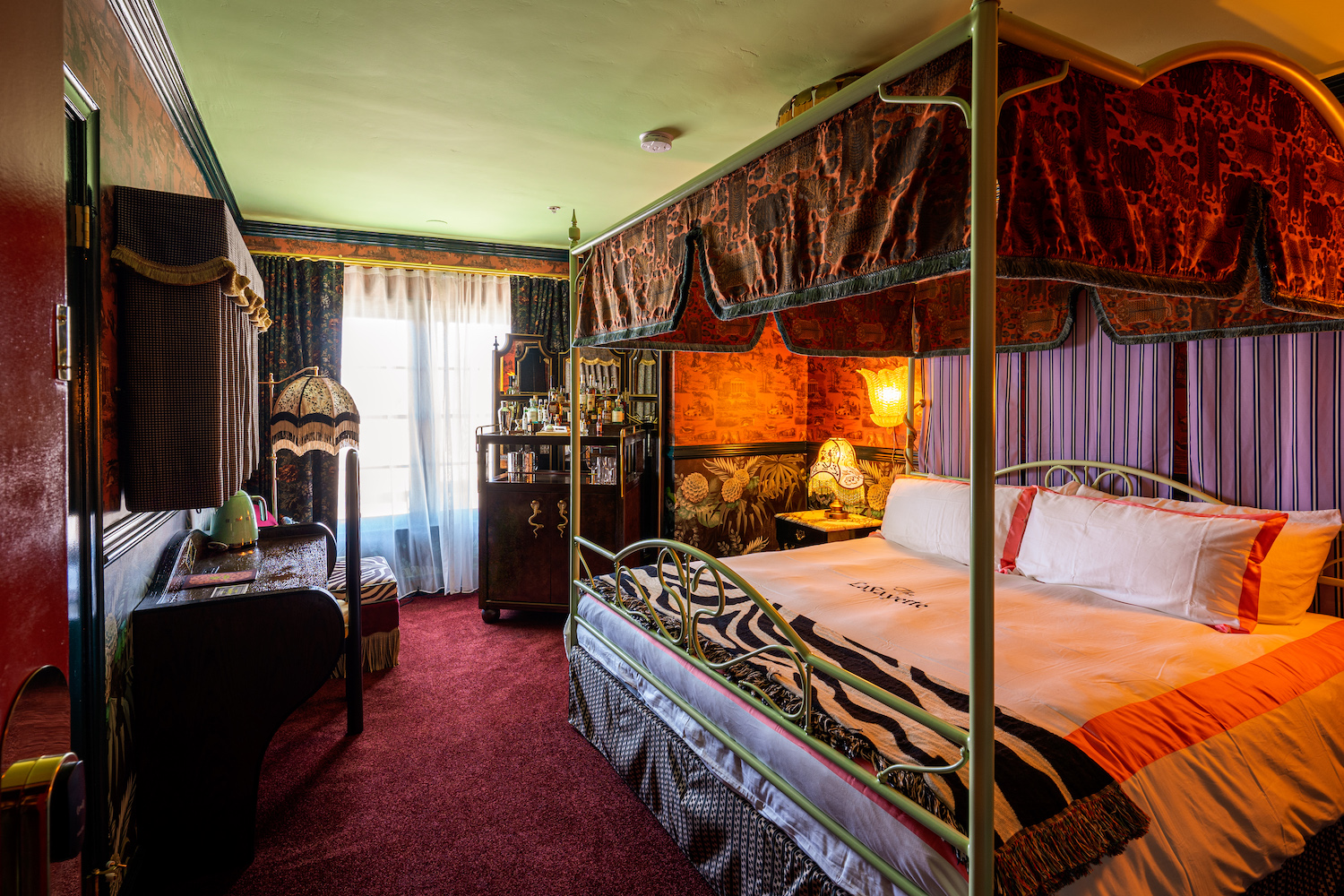Victorian-style hotel room with bedding, a bar and dresser