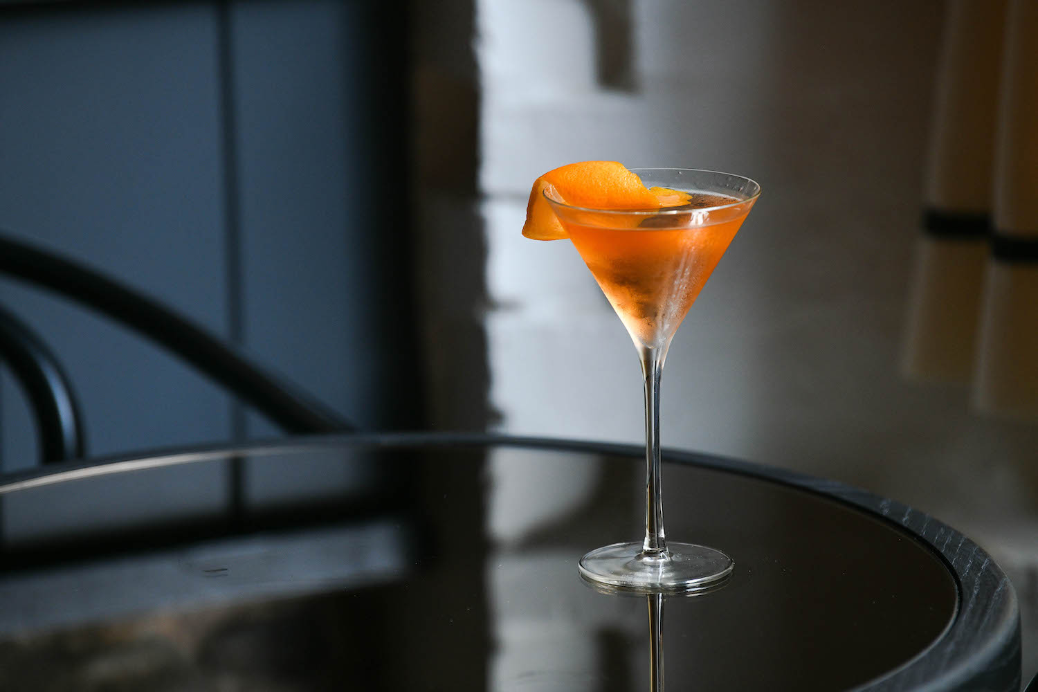 tequila cocktail with an orange garnish served in a martini glass on a table
