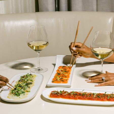 Spread of wine and food being picked up by chopsticks on a table
