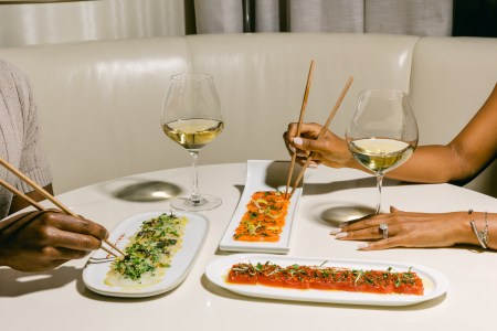 Spread of wine and food being picked up by chopsticks on a table