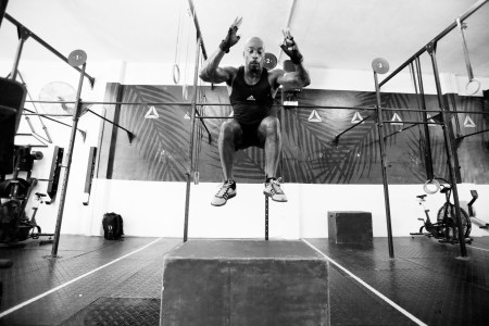 A man performing box jumps in a gym.