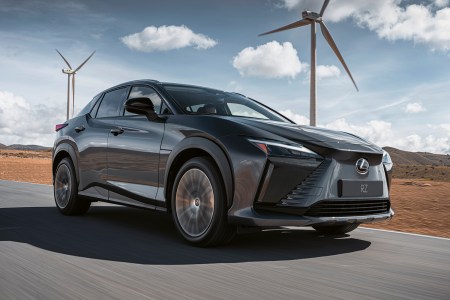 The 2023 Lexus RZ 450e, the brand's first EV, driving with windmills in the background