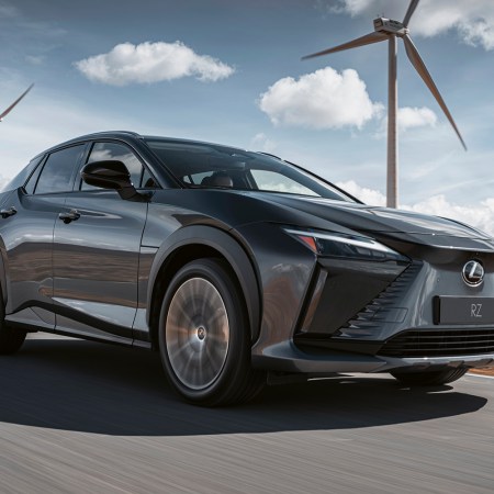 The 2023 Lexus RZ 450e, the brand's first EV, driving with windmills in the background