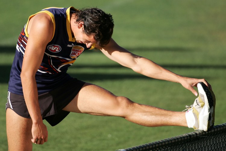 A muscular rugby player stretching.