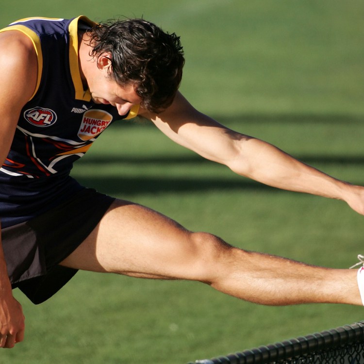 A muscular rugby player stretching.