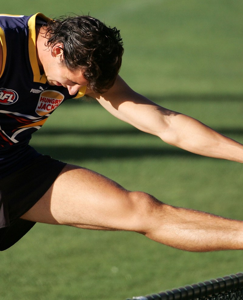 A muscular rugby player stretching.