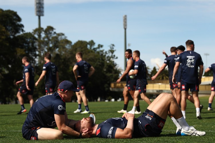 A rugby player getting his neck massaged.