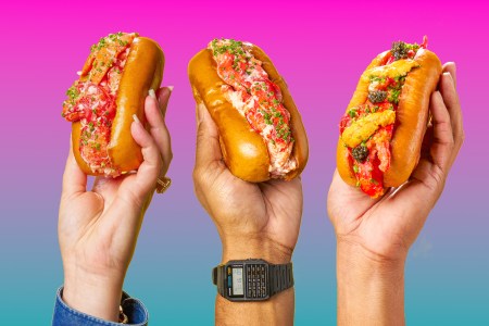 Three lobster rolls being held up in the air