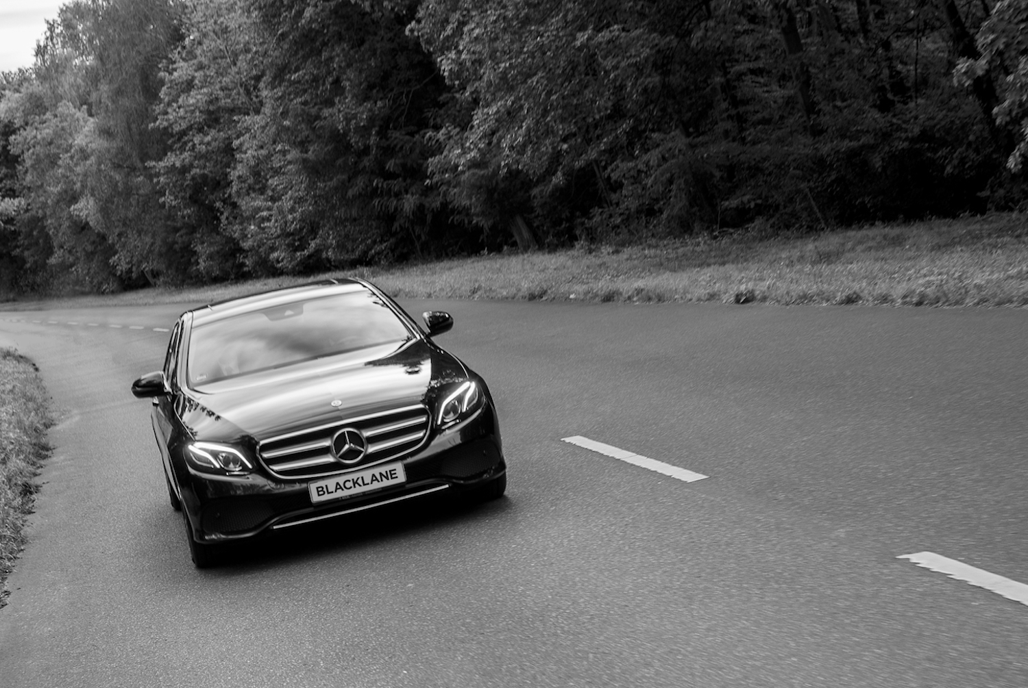 B&W photo of a car driving on a street