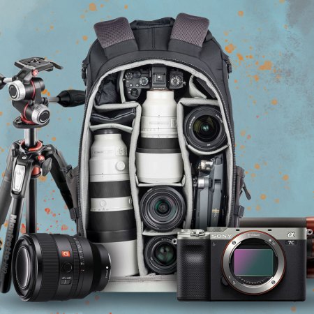 A tripod, camera lens, camera backpack, lighting and camera gear
