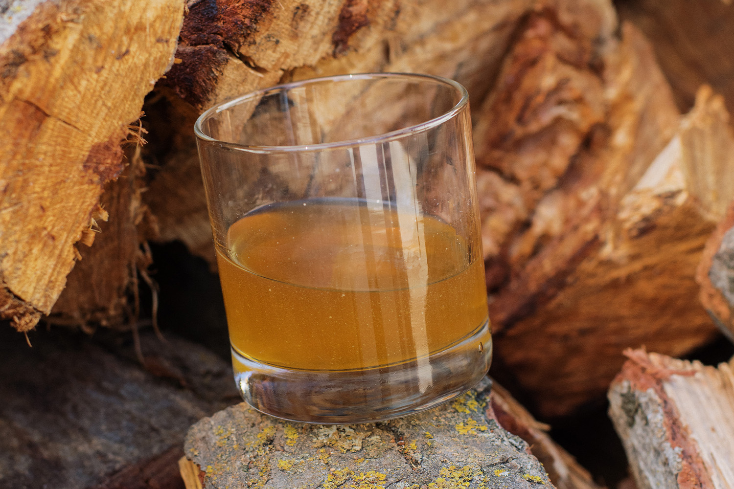 Brownish-gold-colored drink in a lowball glass outside