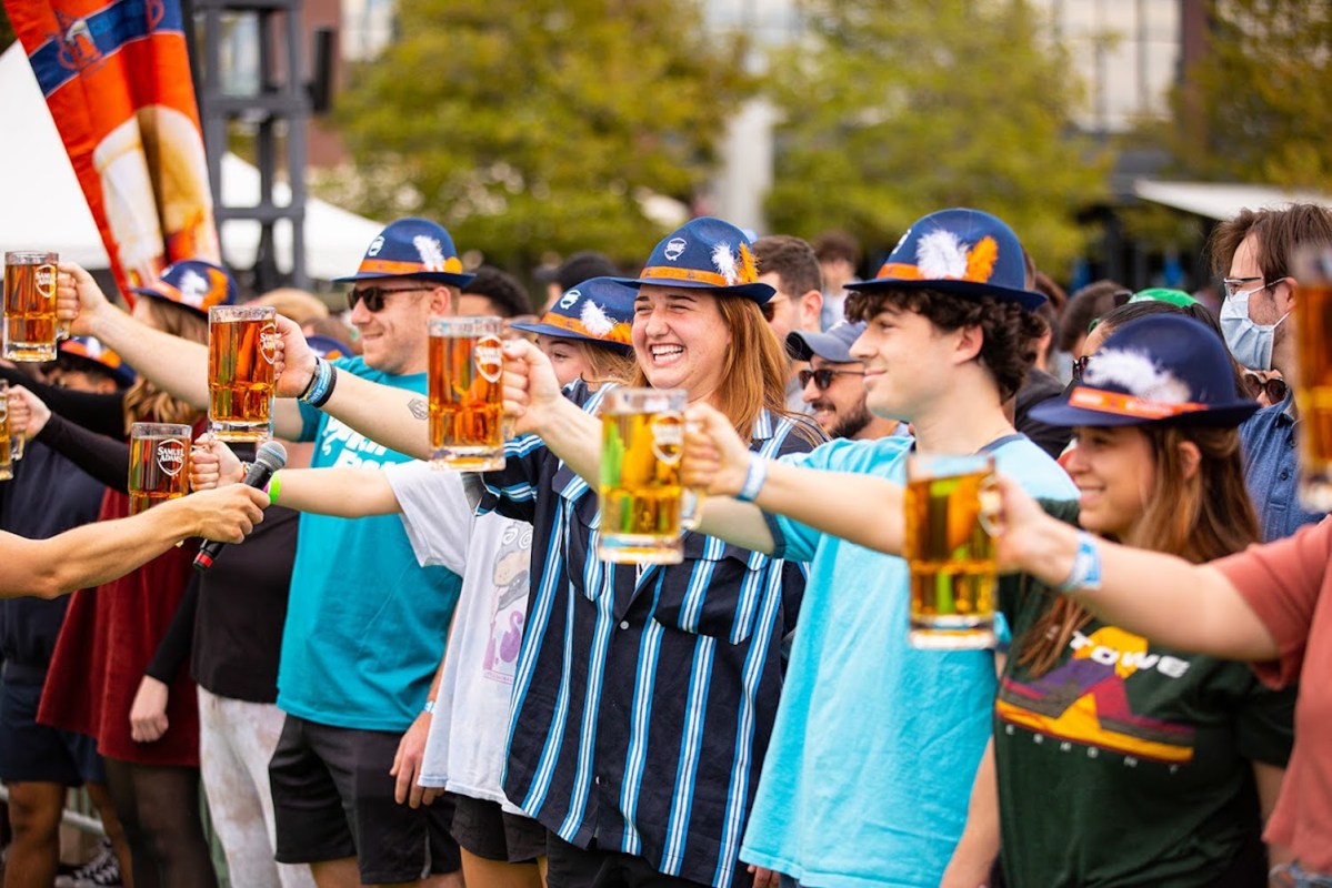 Group of people holding out mugs of beer