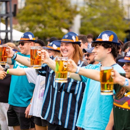 Group of people holding out mugs of beer