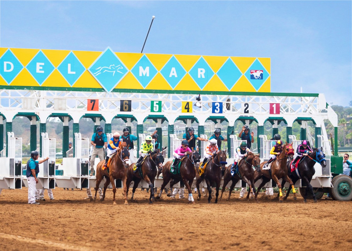 Horses galloping out of the starting gate at the Del Mar Racetrack in California