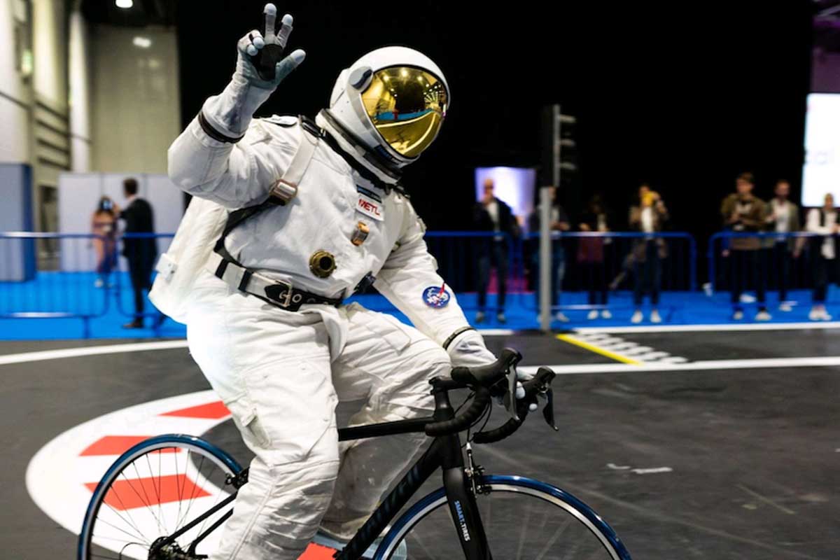 A man in spacesuit riding on a bike that has METL wheels, utilizing material that was developed by NASA