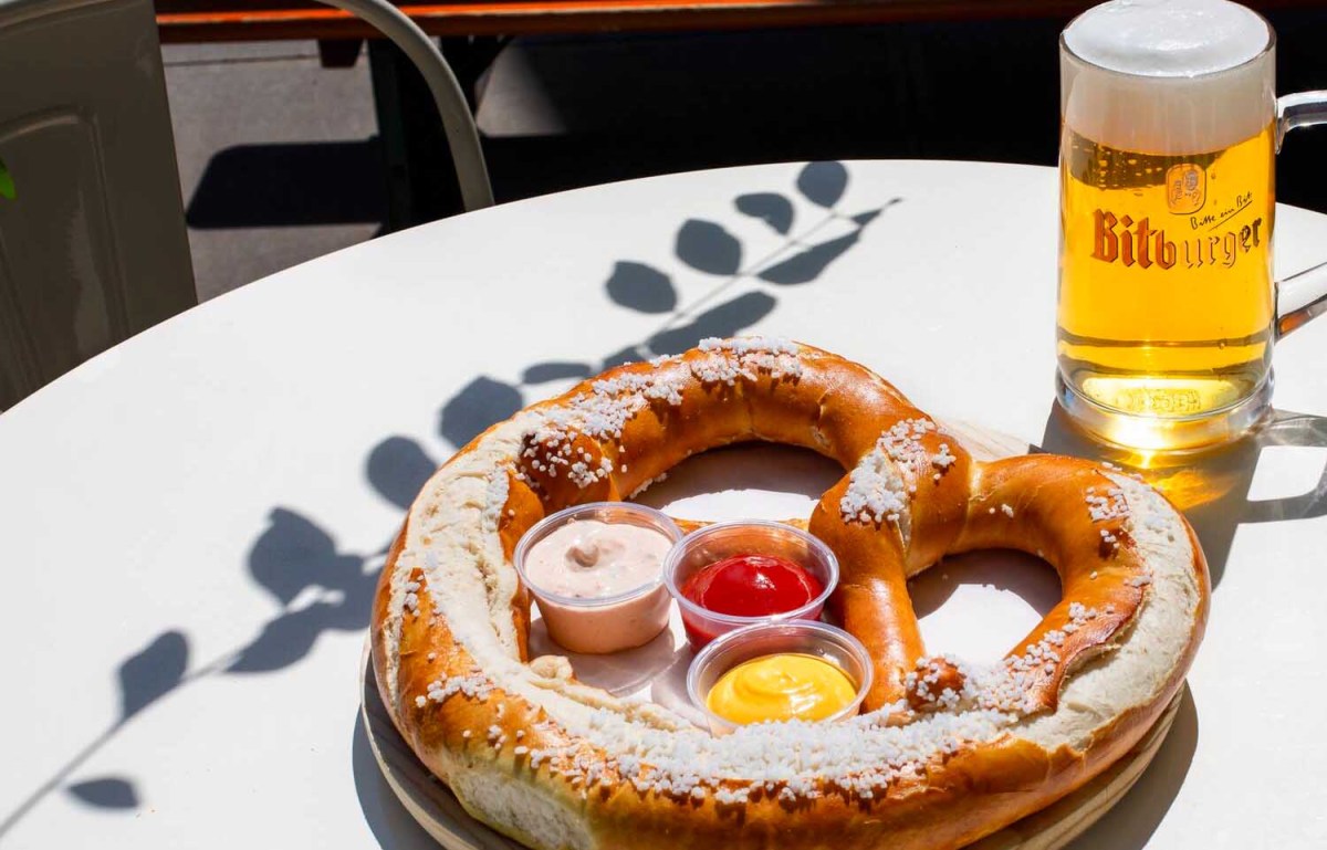 a pretzel on a plate with three dips